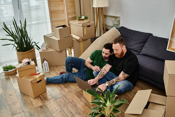 Two men in love taking a break on top of a sofa in a new home filled with relocation boxes. - Фото, зображення