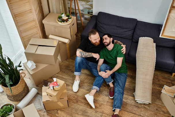 Gay pár sedí na dřevěné podlaze a přemýšlí o svém novém životě, když se stěhují do svého nového domova.. - Fotografie, Obrázek