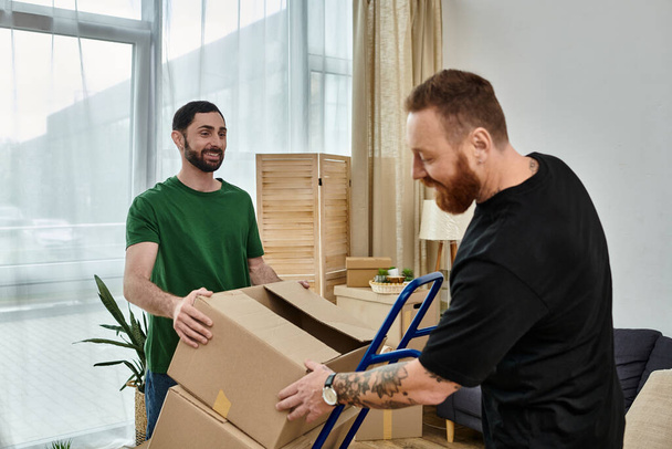 Ένα γκέι ζευγάρι ερωτευμένο ξεπακετάρει κουτιά στο νέο τους σπίτι, συμβολίζοντας μετεγκατάσταση και νέα ξεκινήματα. - Φωτογραφία, εικόνα