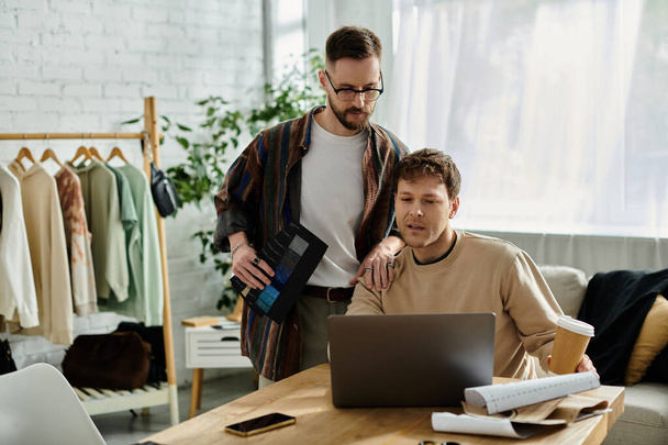 Zwei Männer, Partner im Design, diskutieren bei einem Laptop in einem stylischen Bekleidungsgeschäft über Ideen. - Foto, Bild