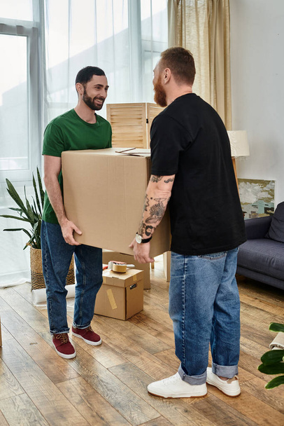 Zamilovaný homosexuální pár, obklopený krabicemi, si vychutnává okamžik, kdy stojí vedle sebe ve svém novém obýváku. - Fotografie, Obrázek