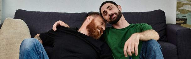 Couple d'hommes refroidissant sur le canapé élégant, embrassant un nouveau chapitre dans un cadre confortable. - Photo, image