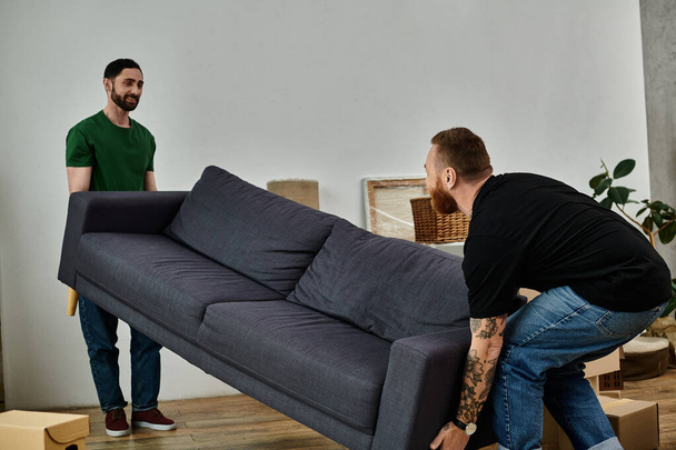 Homopariskunta onnellisesti siirtyy sohva uudessa olohuoneessa, alkaen tuoreena uudessa kodissa. - Valokuva, kuva