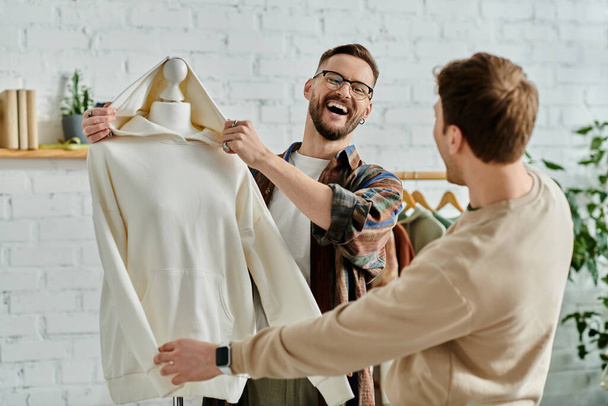 Un uomo tiene con attenzione un vestito su un manichino in un laboratorio di designer. - Foto, immagini
