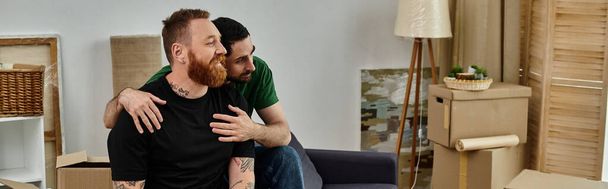 Két férfi szenvedélyesen ölelkezik a dobozok között egy új nappaliban, megtestesítve a szerelmet és az új kezdetet.. - Fotó, kép