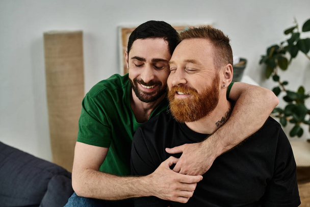 An affectionate moment between two men embracing in a living room filled with moving boxes, symbolizing a fresh start in their new home. - Photo, Image