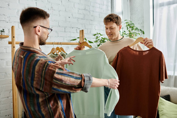 gayové pár obdivovat tričko na stojanu v designérské dílně. - Fotografie, Obrázek
