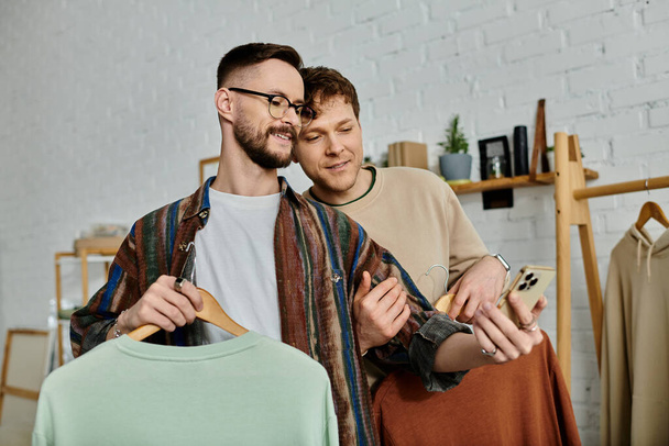 Dwóch mężczyzn, para gejów, stoi ramię w ramię w warsztacie projektantów, współpracując nad modnym strojem. - Zdjęcie, obraz