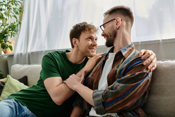 Gay couple creating trendy attire, sitting together on top of a couch in a designer workshop. - Photo, Image
