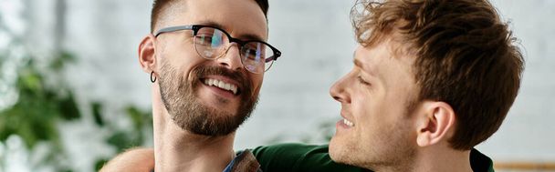 Deux hommes, un couple gay, se tiennent étroitement unis alors qu'ils travaillent ensemble dans un atelier de design créant des vêtements tendance. - Photo, image