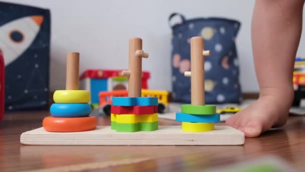 Piernas de un niño de 1-2 años de edad primer plano jugando con pirámides de juguete, juguetes educativos en una habitación para niños en el suelo. Imágenes de alta calidad 4k - Metraje, vídeo