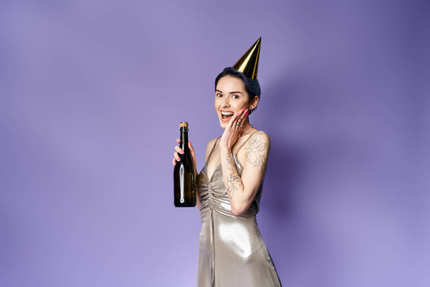 Young woman with short blue hair, wearing a silver party dress and hat, holding a champagne bottle. - Fotoğraf, Görsel