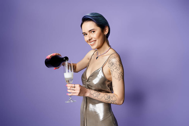 Young woman with short blue hair looking elegant in a silver dress, holding a glass of champagne at a party. - Foto, imagen