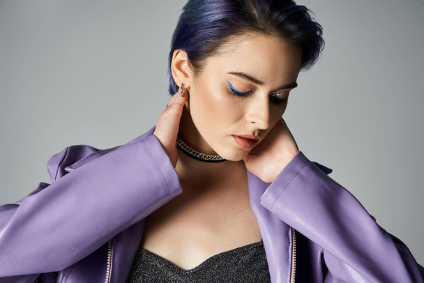 A stylish young woman with blue hair striking a pose in a purple jacket in a studio setting. - Фото, зображення