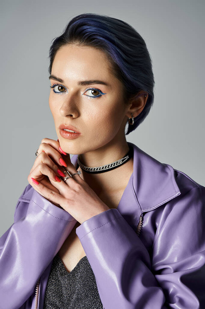 A fashionable, young woman with short dyed hair poses in a stylish purple jacket in a studio setting. - Foto, Bild