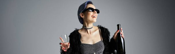 A stylish young woman with short dyed hair striking a pose in a black dress while holding champagne - Foto, Imagem