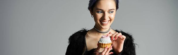 Stylish birthday girl with dyed hair holds a scrumptious cupcake in her hands. - Foto, afbeelding