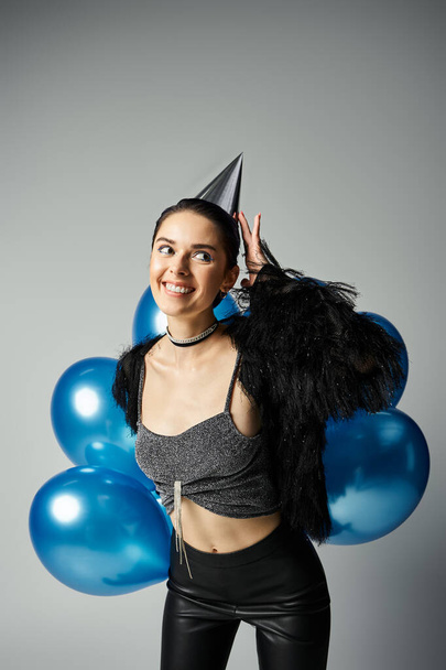 A stylish young woman with short dyed hair celebrates with a party hat and a bunch of colorful balloons. - Foto, immagini