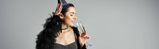 Stylish young woman in black dress holding champagne glass. - Zdjęcie, obraz