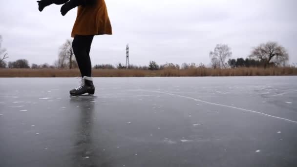Pieds femelles patinant sur une rivière ou un lac gelé. Jambes de femme enfilées de patins artistiques glissant sur la glace en pleine nature. Jeune fille améliorer les compétences et avoir des loisirs actifs par temps froid d'hiver. Mouvement lent. - Séquence, vidéo