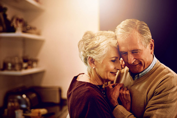 Senior couple, dancing and love in the kitchen to celebrate anniversary date, dinner or lunch at home. Happy, smile and elderly man or woman bonding, together for romance and marriage for happiness. - Photo, Image