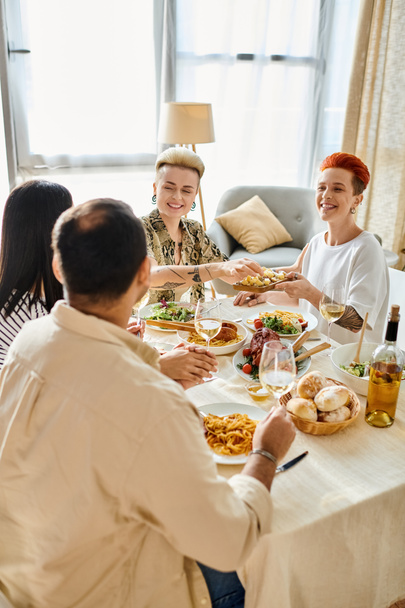 Różnorodna grupa dzieląca posiłek, w tym kochająca się para lesbijek. - Zdjęcie, obraz