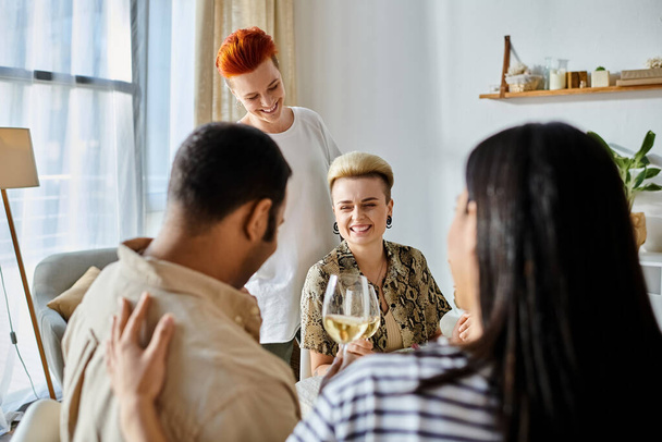 Διαφορετική ομάδα φίλων, συμπεριλαμβανομένου ενός αγαπημένου λεσβιακού ζευγαριού, απολαμβάνουν το κρασί γύρω από ένα τραπέζι. - Φωτογραφία, εικόνα