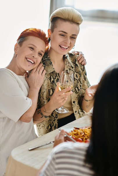 Дві жінки стоять за столом, частина різноманітної групи, насолоджуючись їжею. - Фото, зображення