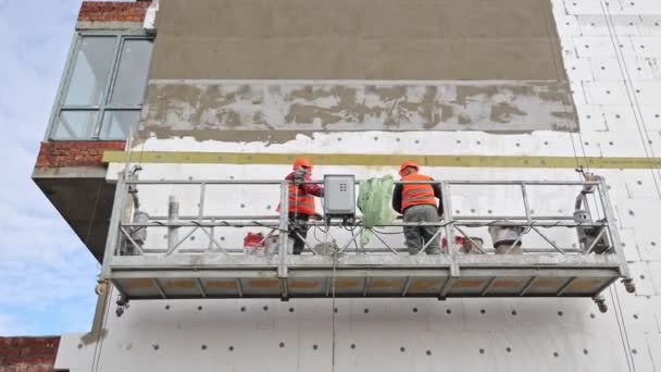 Construction Workers Insulating Building Facade,Two construction workers in reflective vests working on scaffolding, applying insulation to a buildings facade - Footage, Video