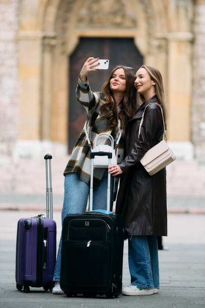 Couple de deux touristes féminines qui aiment explorer les villes européennes, concept de tourisme et de voyage, femmes avec valises se promenant dans la ville, couple de femmes modernes lgbt se promenant dans la ville.  - Photo, image