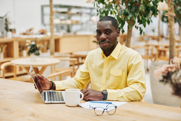 Мужской портрет работает сидящий бизнесмен офисный компьютер африканской американской технологии глядя один профессиональный мужчина бизнес человек черный взрослый современный образ жизни ноутбук молодой беспроводной - Фото, изображение