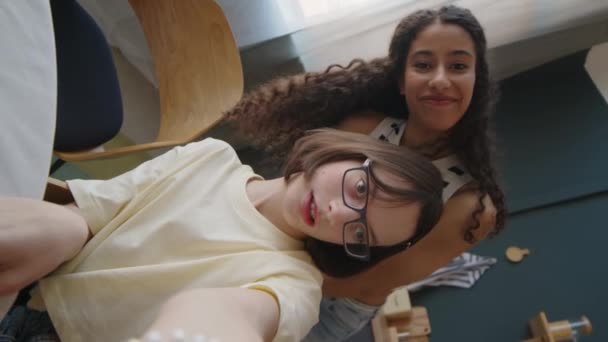 Вертикальный ручной снимок белой девочки-подростка с мозговой вечеринкой, снимающей видеоблог с лучшей подругой-бирасиалом, проводящей время вместе дома - Кадры, видео
