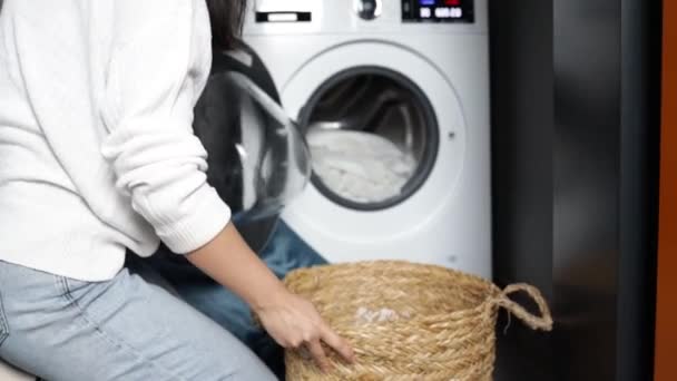 Nainen vetää puhtaita valkoisia liinavaatteita pesukoneesta. Ladataan pesukone. Ladatkaa vaatteet pesukoneeseen. Kuormavaatteiden pesu. - Materiaali, video