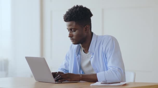 Διάλειμμα στη δουλειά. Νέος αφρικανός διευθυντής χαλαρώνοντας στο χώρο εργασίας μετά την ολοκλήρωση του έργου στο laptop - Πλάνα, βίντεο