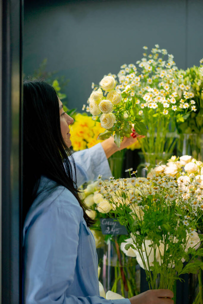loja de flores uma menina perto do balcão com flores escolhe as flores necessárias e um arranjo de flores - Foto, Imagem