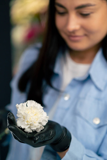 loja de flores uma menina perto de uma mesa branca recolhe um arranjo de flores de um belo buquê de flores brancas - Foto, Imagem