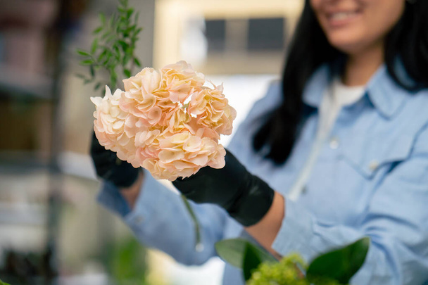 fechar a loja de flores uma menina perto de uma mesa branca recolhe um arranjo de flores de um belo buquê de flores brancas - Foto, Imagem