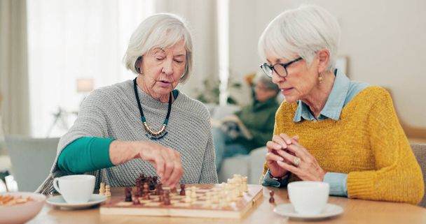 Пожилая женщина, друзья и игра в шахматы за столом для социальной активности, принятия решений или стратегической игры дома. Пожилые женщины наслаждаются соревновательными настольными играми, чтобы повеселиться вместе в доме престарелых. - Фото, изображение