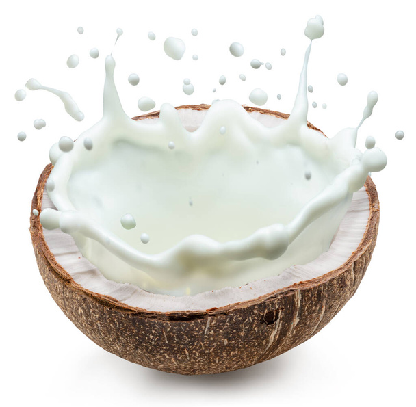 Kokosmelk spat uit de helft van het kokosfruit. Bestand bevat clipping pad. - Foto, afbeelding