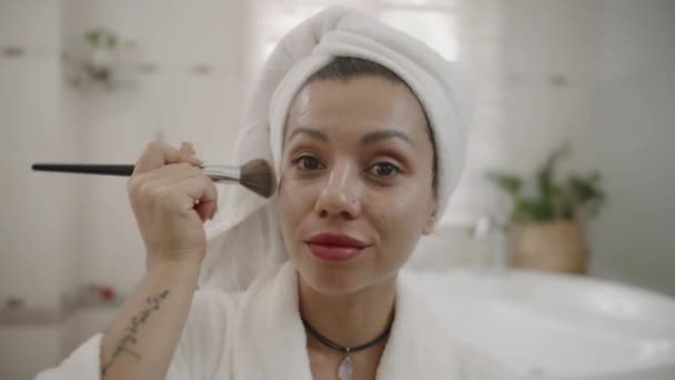 POV van aantrekkelijke blanke vrouw met handdoek op het hoofd doen gezicht contouren met borstel in de badkamer - Video