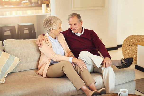 Hug, love and retirement with senior couple on sofa in living room of home together for bonding. Happy, relax or security with elderly man and woman in apartment for commitment, marriage or weekend. - Photo, Image