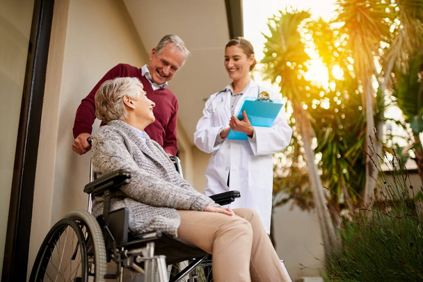 Oudere, arts en persoon met een handicap in bejaardentehuis voor gezondheid, ondersteuning of hulp voor de patiënt. Oudere, man of duwende vrouw met rolstoel in zorginstelling, zorgverlener met rapport voor medische. - Foto, afbeelding