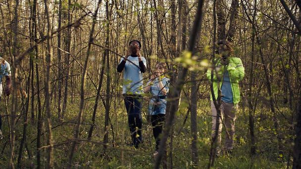 Grupo de voluntarios salvavidas en busca de una persona desaparecida, llamando a su nombre en el bosque y pasando por los árboles para seguir los pasos. Escuadrón de rescate en busca de una víctima perdida. Cámara B. - Foto, imagen