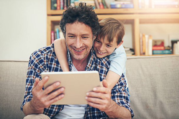 Boldog, tabletta és gyermek ölelés apa otthon nézi a filmeket, rajzfilmek és online szórakozás. Család, szerelem és apa a fiával a digitális technológia az internet, video hívás és pihenjen hétvégén kanapén. - Fotó, kép
