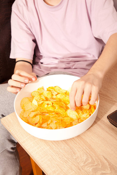 Кавказка в розовой футболке с белой тарелкой картофельных чипсов и готовится к еде - Фото, изображение