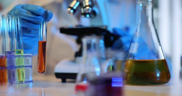 Bilim adamı laboratuvarda kırmızı turuncu sıvı test tüplerine kimyasalları karıştırıyor. Laboratuvarda zehirli çözücüler üzerinde çalışıyorum. - Video, Çekim