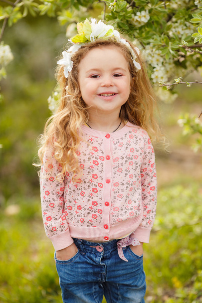 Portrait of little girl outdoors in a lush garden. - Foto, afbeelding
