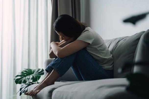 Unhappy lonely depressed woman is sitting on the couch and covering her face with her hands, depression concept - Photo, Image