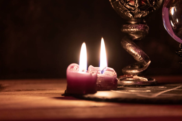 Un detallado primer plano de dos velas rosas encendidas con un fondo oscuro y místico, enfatizando un tema ritualista - Foto, Imagen