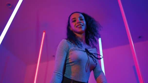 Kis látószögű kamera spanyol táncosból, ahogy a kamerába néz és a városi popzenére táncol. Professzionális vonzó hipster mozog hip hop dal lila led vagy neon fény. Stílusos ruha. Regnálás. - Felvétel, videó